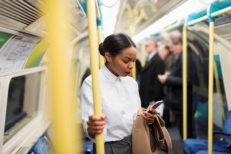 Businesswoman in underground train looking at cell phone